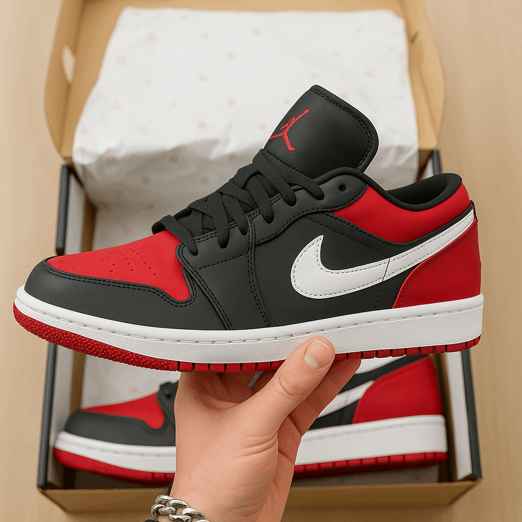 Red and black sneaker held by a hand with a box in the background