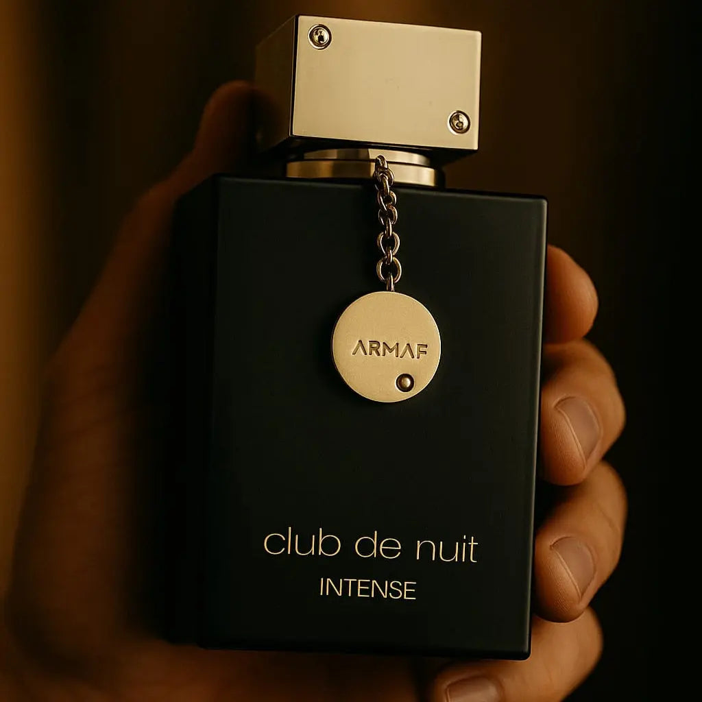 Black Armaf Club de Nuit Intense perfume bottle held in a hand against a dark background