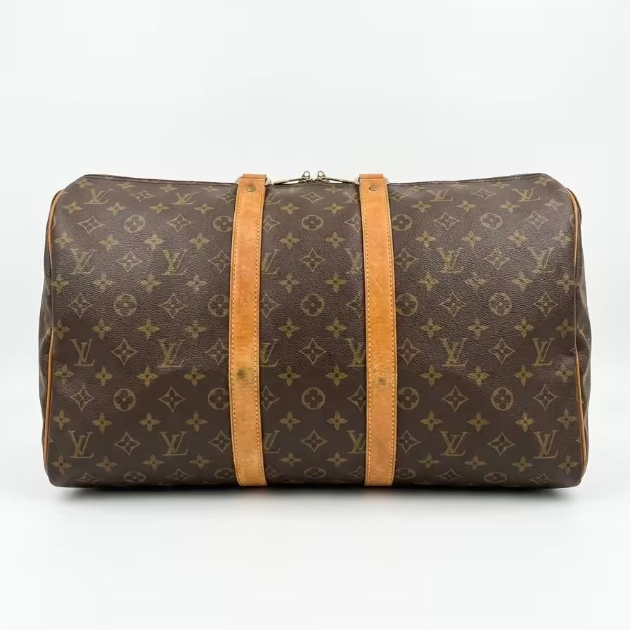 Underneath base view of an authentic Louis Vuitton Keepall monogram travel duffle bag, showing clean canvas corners and the full length of the twin vachetta leather support straps.