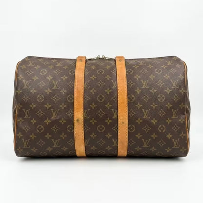 Underneath base view of an authentic Louis Vuitton Keepall monogram travel duffle bag, showing clean canvas corners and the full length of the twin vachetta leather support straps.