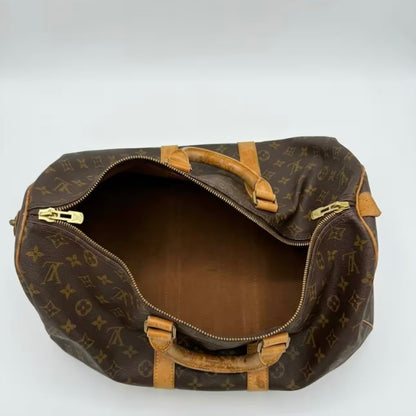 Overhead open view of an authentic Louis Vuitton Keepall duffle bag, demonstrating a wide-access interior compartment with clean canvas lining and securely stitched vachetta handles.