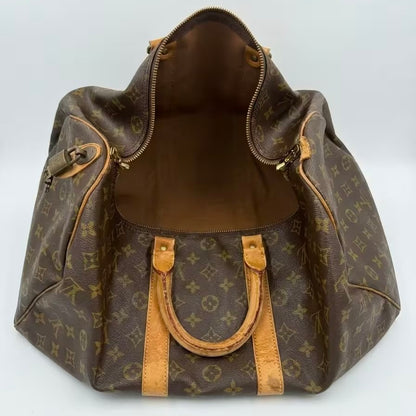 Wide front-open view of an authentic Louis Vuitton Keepall monogram duffle bag, showcasing the flexible canvas construction, rich brown lining, and attached brass padlock detail.
