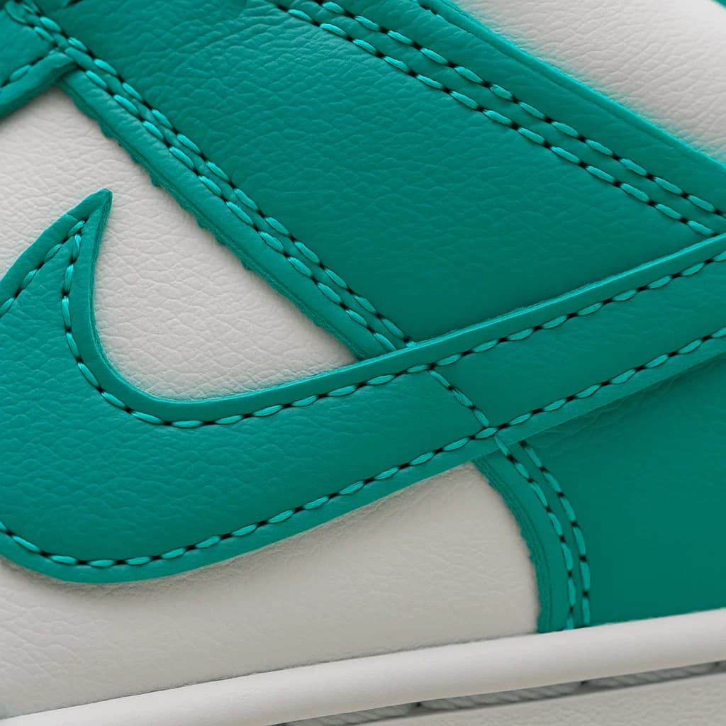 Close-up of a teal and white sneaker with a prominent brand logo.