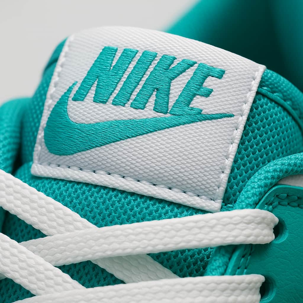 Close-up of a teal Nike sneaker with white laces and logo.