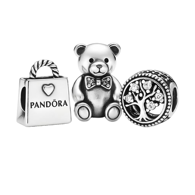 Three Pandora charms including a teddy bear, a shopping bag, and a circular charm with a tree design on a white background.