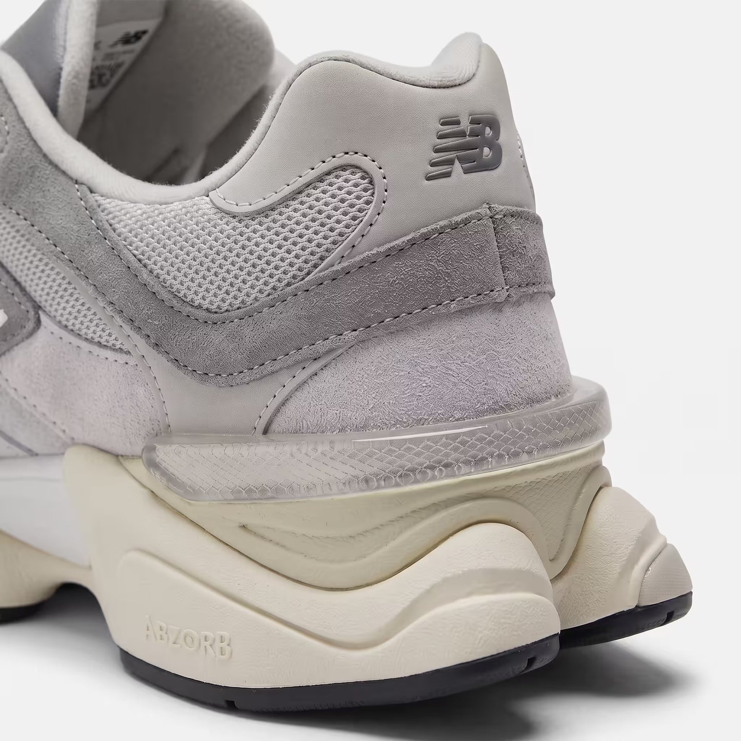 Close-up technical detail of the heel of the New Balance 9060 Rain Cloud Grey, showing the signature translucent plastic CR device, fine stitching on the heel panel, and technical collar mesh