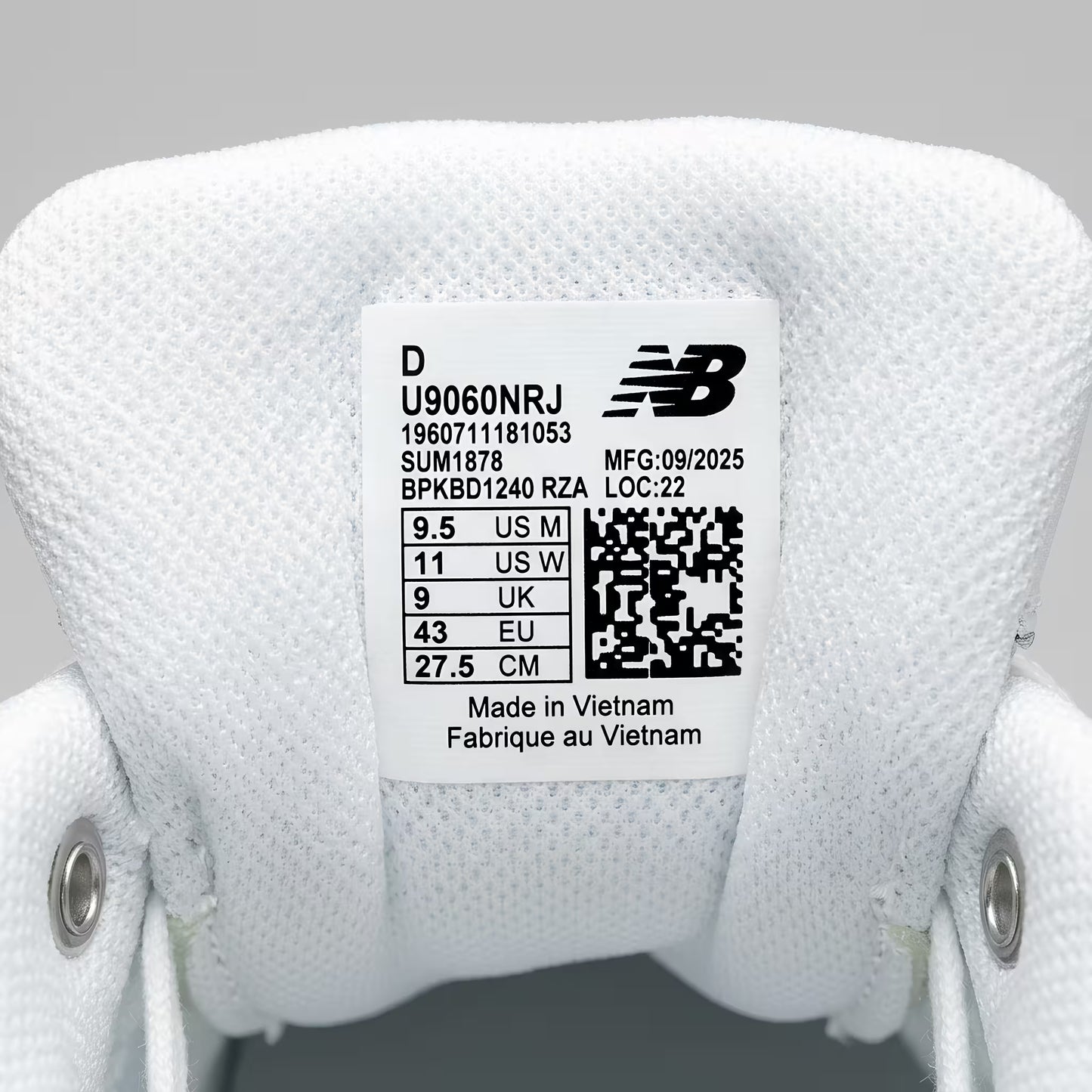 Close-up of a New Balance 9060 label on a white sneaker with product sizing details.
