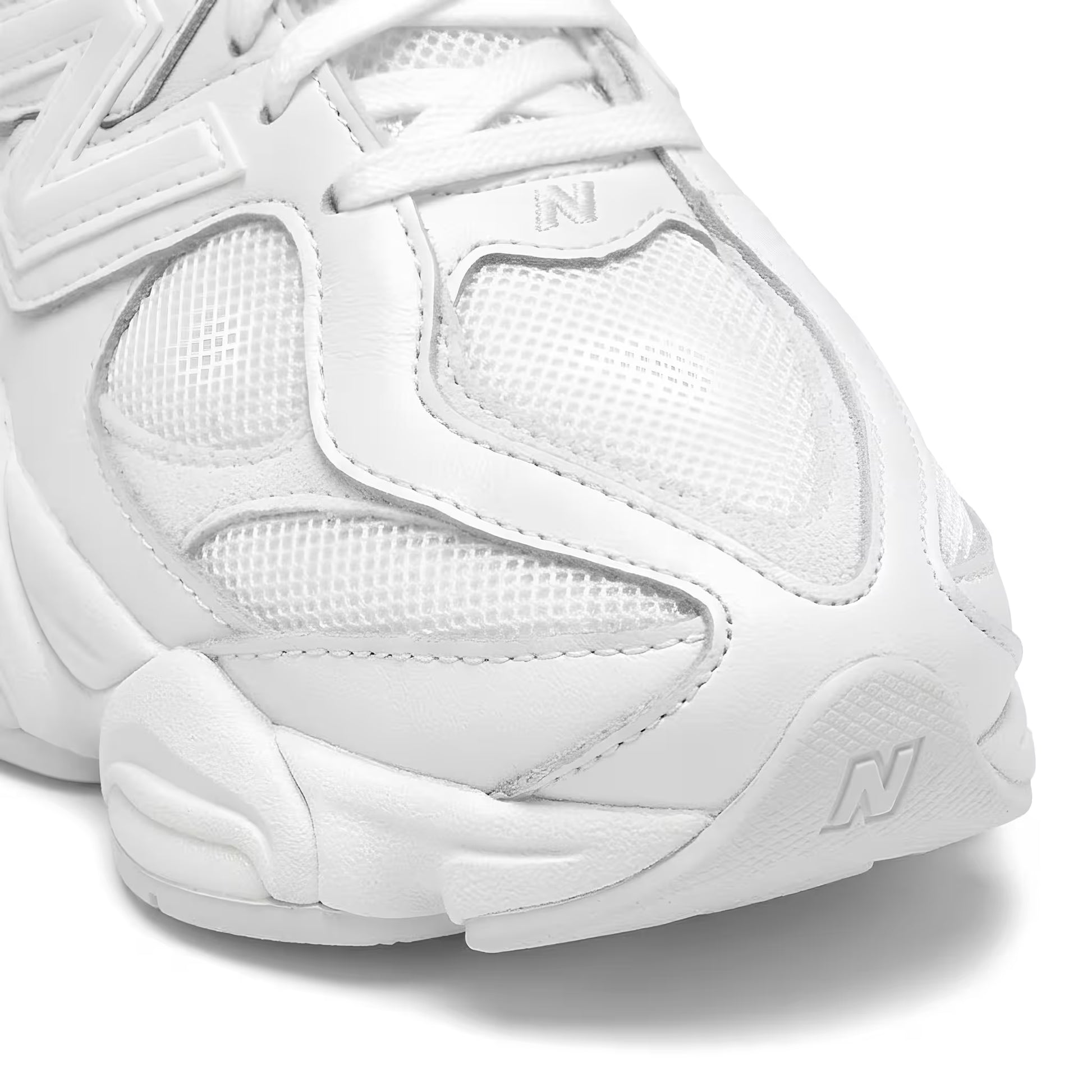 White new balance 9060 sneaker with New Balance logo on a white background closeup shot of the toe box.
