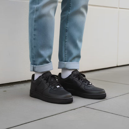Person wearing black nike air force 1 sneakers and light blue jeans on a concrete floor. Lifestyle wearing shot.