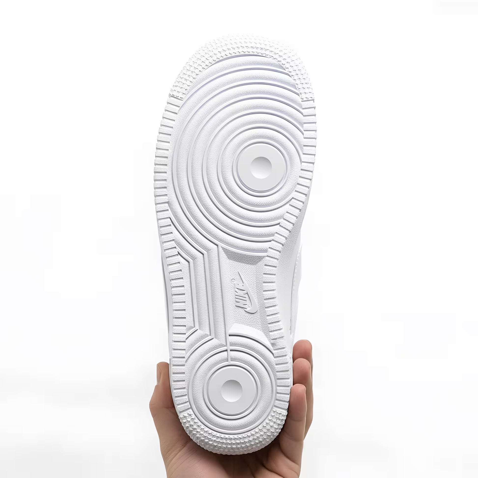 A White Nike Air Force 1 sneaker sole held by a hand on a white background