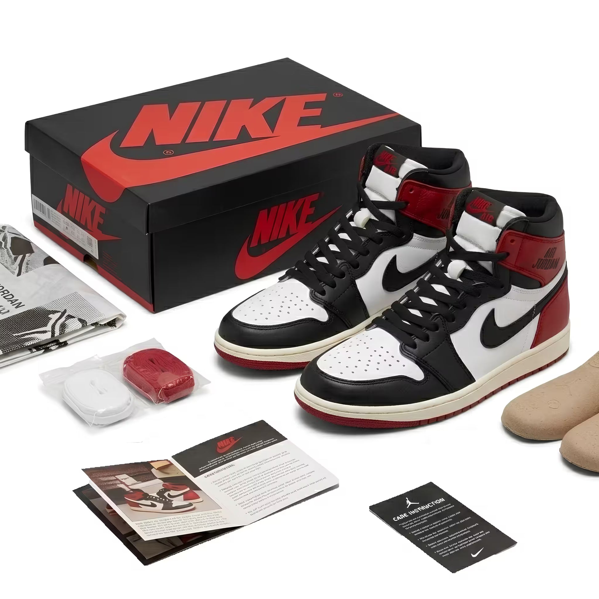 Black, white, and red Nike Air Jordan 1 shoes with packaging and accessories on a white background