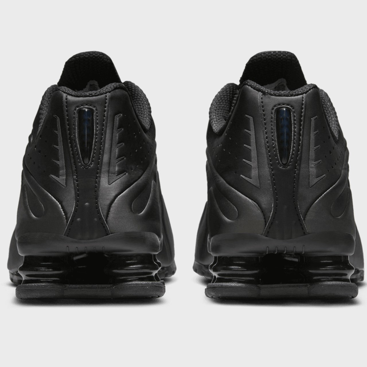 Black athletic shoes with a distinctive sole design on a light gray background