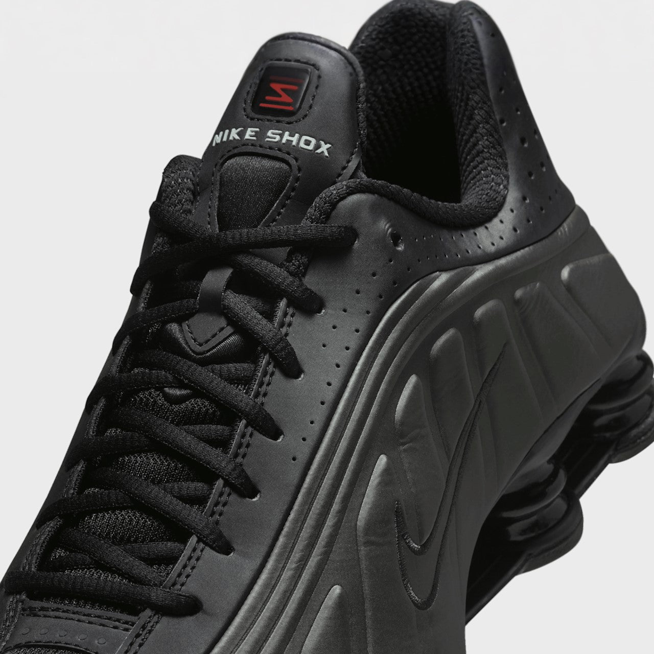 Black Nike Shox sneaker on a light gray background