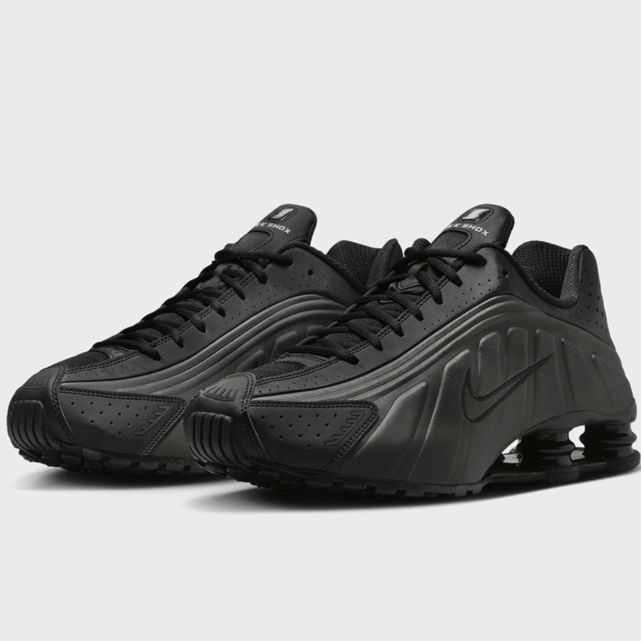 Black athletic shoes with a prominent brand logo on a light gray background