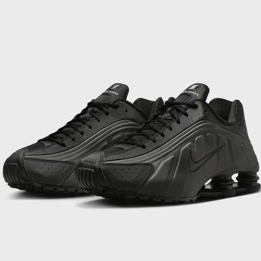 Black athletic shoes with a prominent brand logo on a light gray background